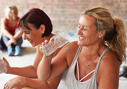 Two friends in their forties are relaxing and sharing a laugh after a workout class