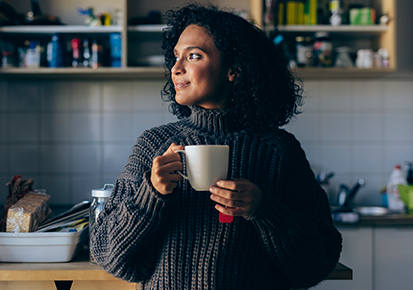 Woman drinking a hot soothing tea at home