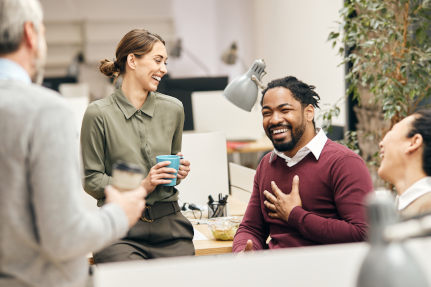 Image of a young black man laughing and talking with a group of professional colleagues colleagues