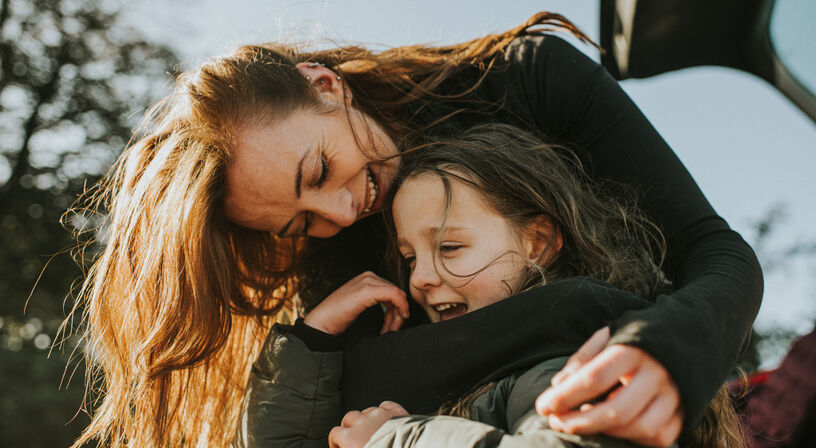 Woman with short blonde hair on the sofa with a mug and magazine, resting on a pillow 