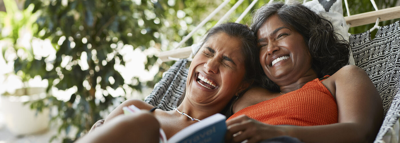 Two girls sat on a hammock, laughing
