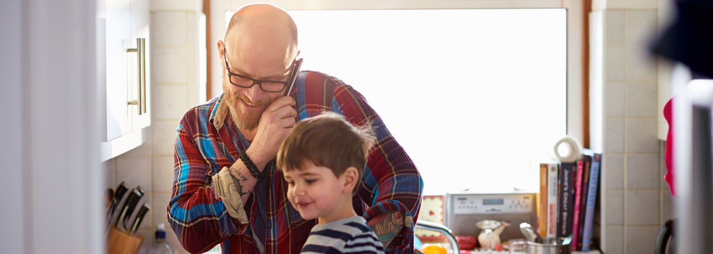 Dad on the phone whilst making lunch for his son