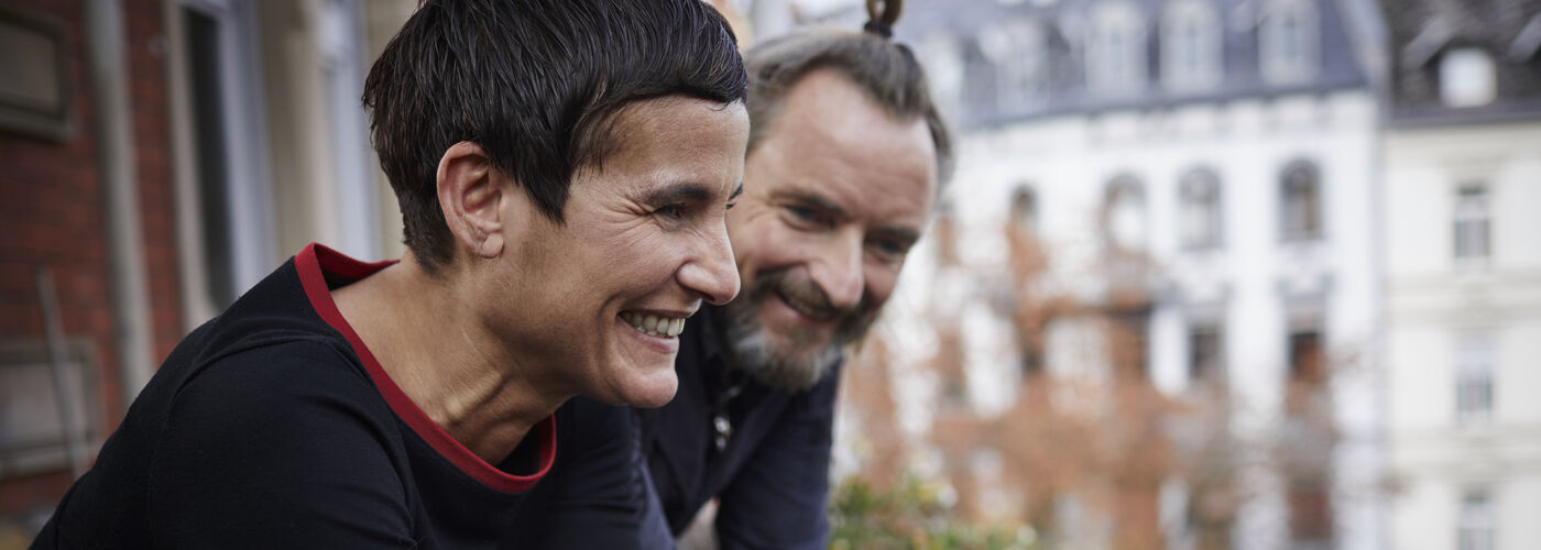 A middle aged couple talking on a balcony