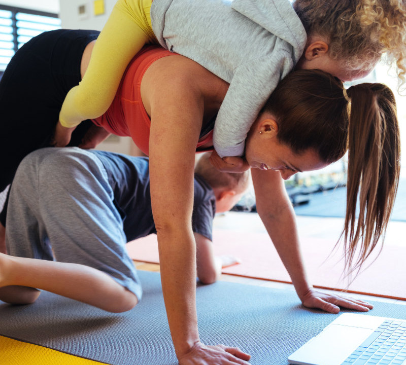 Mother with two kids playfully hanging off her