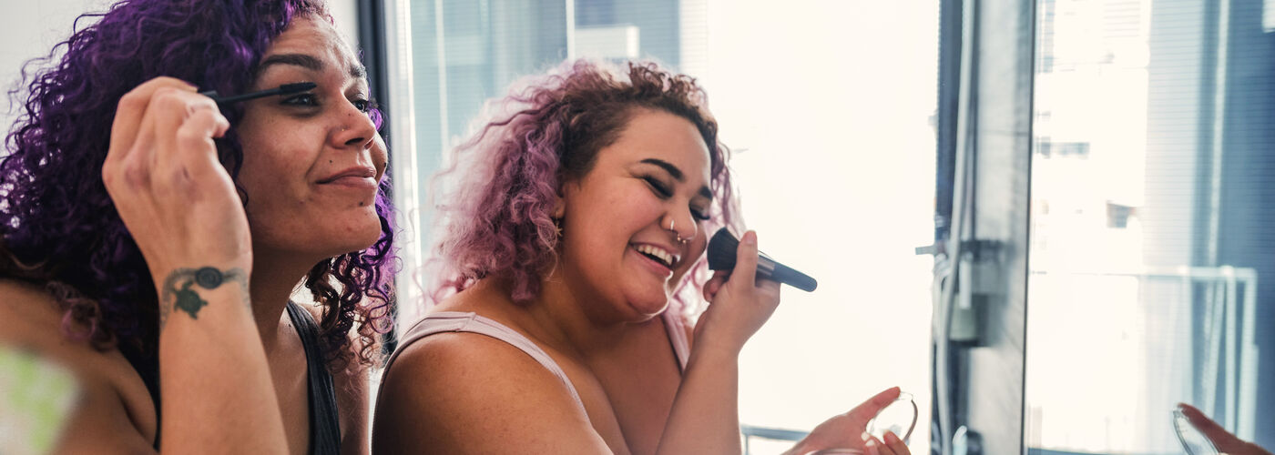two women happily applying make up together