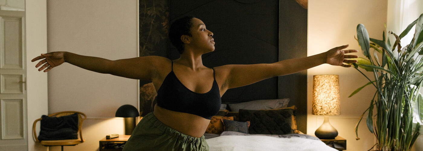 Young woman exercising by bed at home