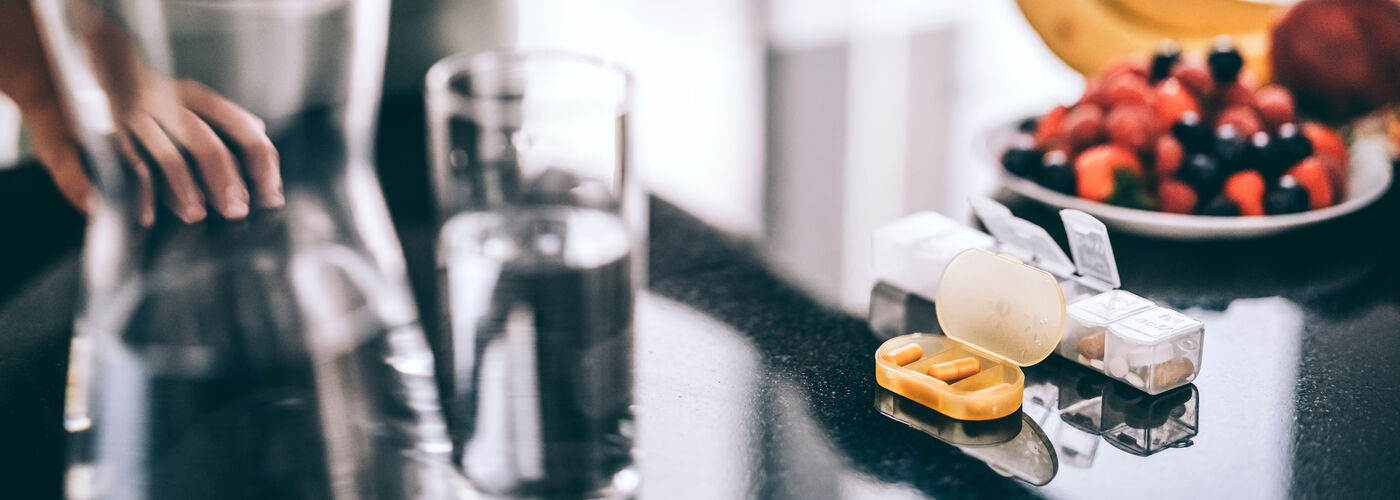 Yellow pills and water on a kitchen counter