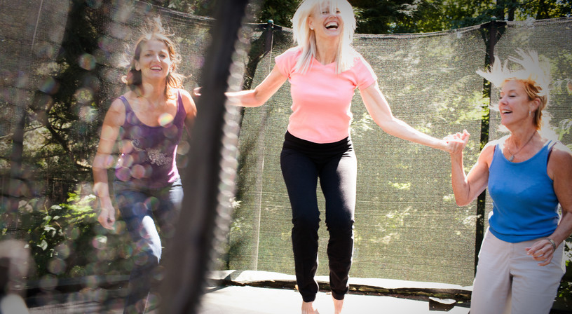 Three women energetically jumping on a trampoline