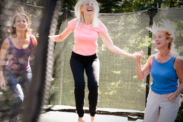 Three women energetically jumping on a trampoline