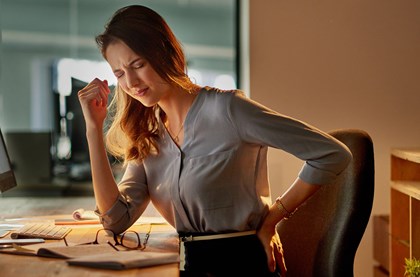 Woman at desk clutching her back in pain