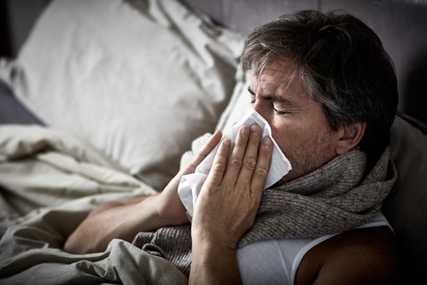 Man blowing nose during illness