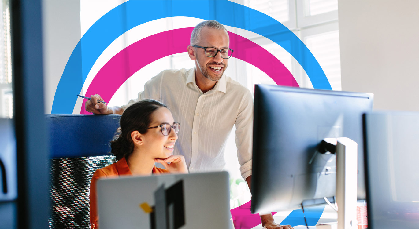 Man and woman in the office both looking at her computer screen