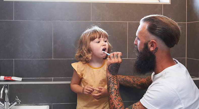 Dad helping to brush daughter's teeth
