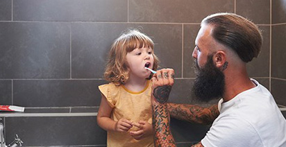 Dad cleaning daughters teeth 