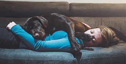 Woman and dog asleep on settee