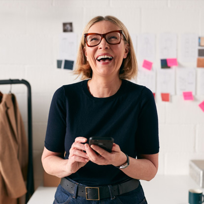 An older female employee is laughing. She appears to work in a creative office.