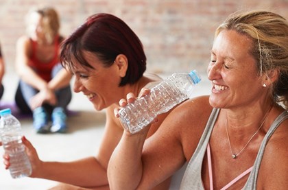 Two friends in their forties are relaxing and sharing a laugh after a workout class