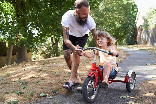Father pushing little girl on a bike