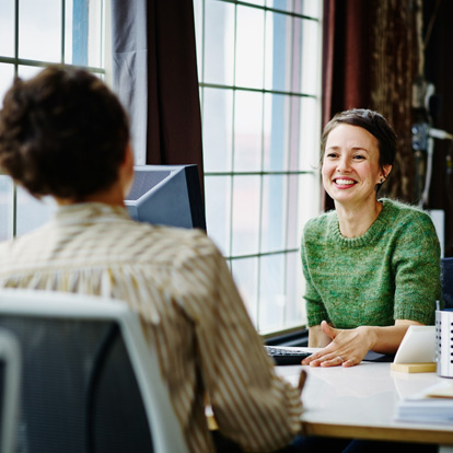 Two colleagues speaking openly together. They're happy at work.