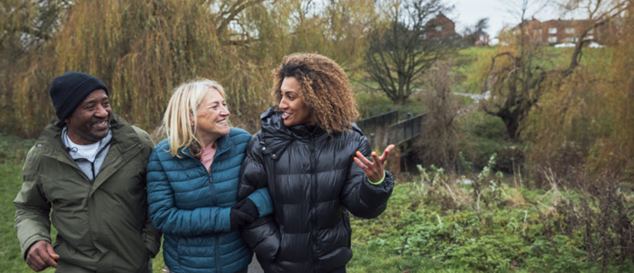 Two parents with their teenage son walking through a field in autumn 