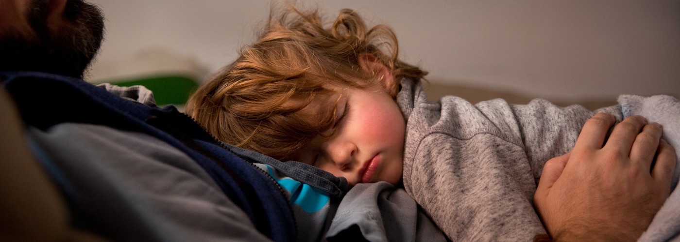 young boy and father asleep on sofa
