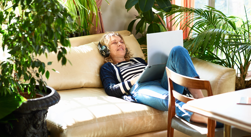 Woman sitting back on sofa using laptop computer