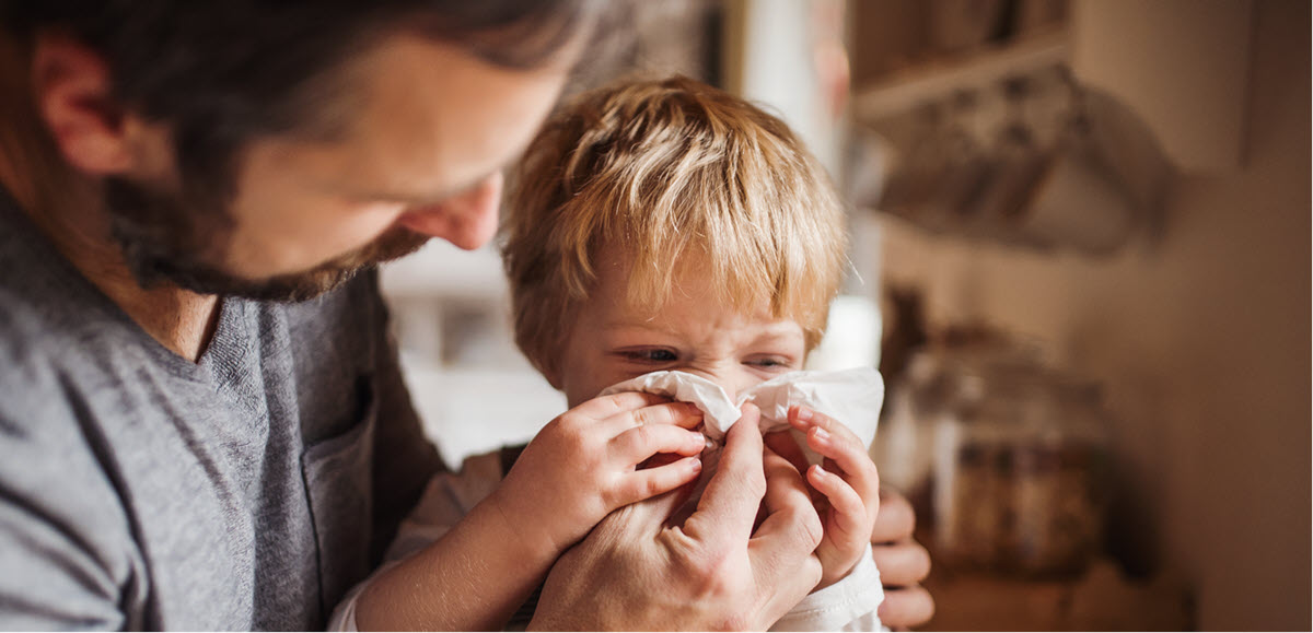 Father helping his young son blow his nose 