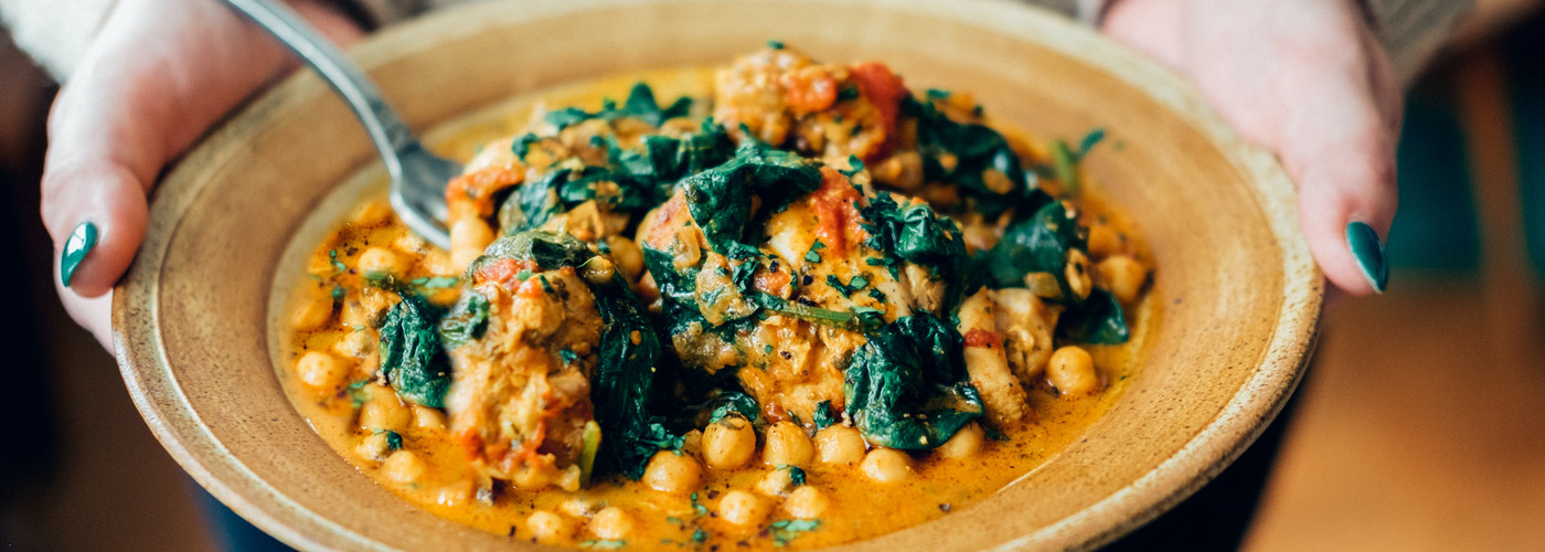 A grey bowl containing a vibrant spinach and chickpea curry 