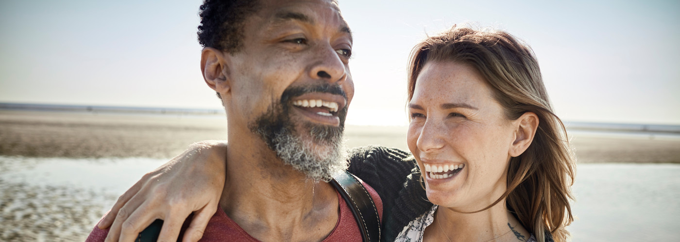 A couple grinning, walking on a beach
