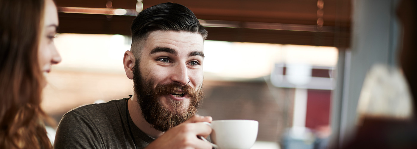 Young man drinking a cup of coffee with a friend 