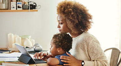 A mother checking her emails with a toddler on her lap