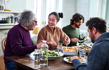 Family sat around dinner table chatting 