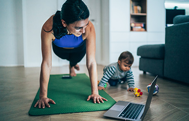Woman practising yoga while young child plays 