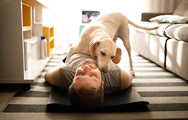 Woman laid on the floor with a dog comforting her 