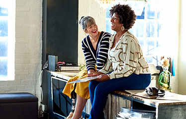 Colleagues sitting on a desk laughing together 