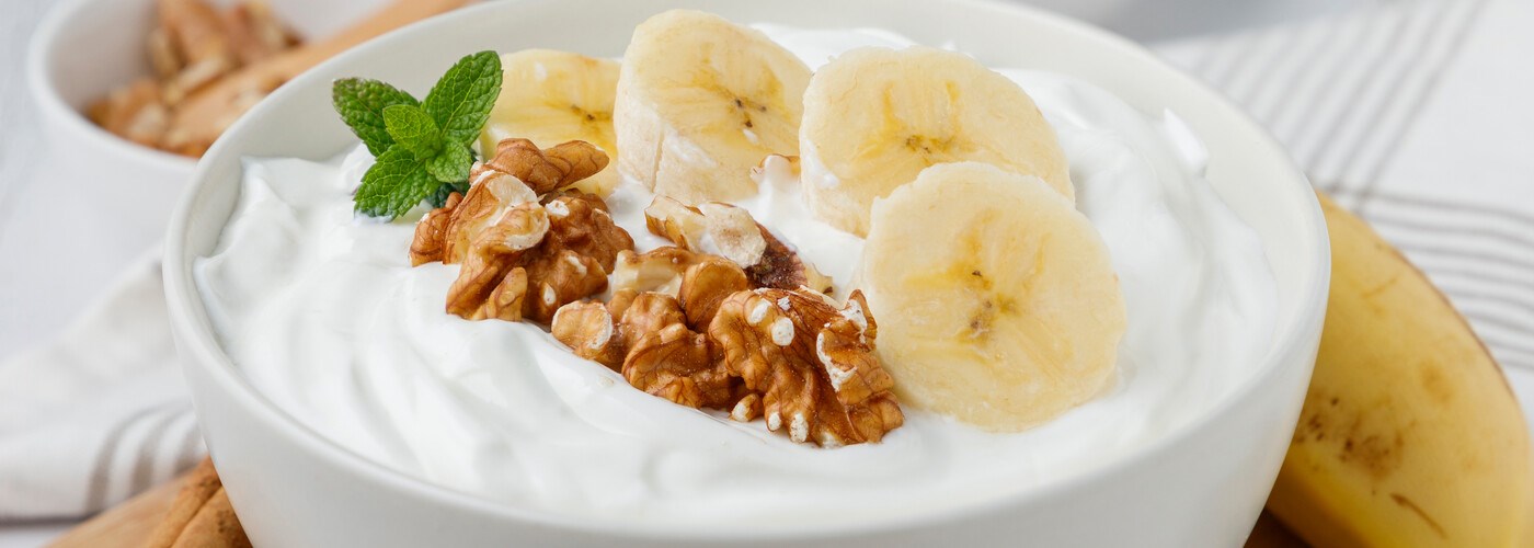 A bowl of greek yoghurt with banana and walnuts. 