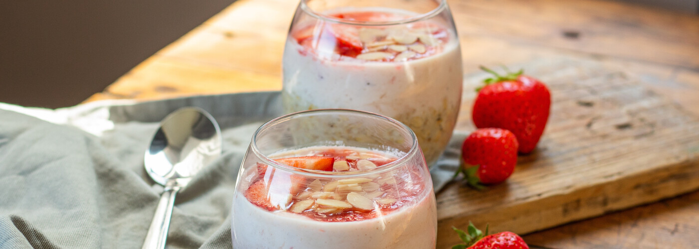 Two portions of strawberry cheesecake overnight oats in a glass jar