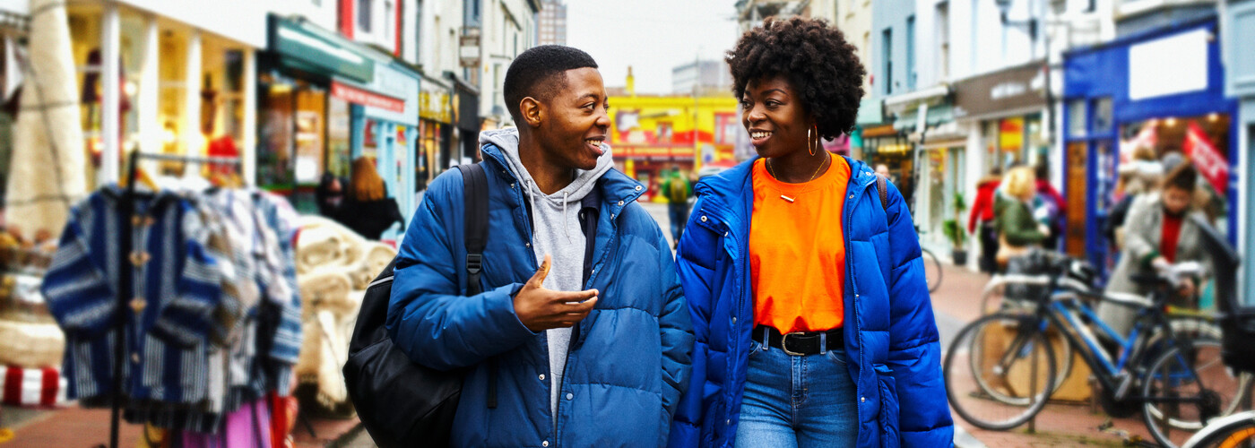 Couple of young adults walking in a town market street
