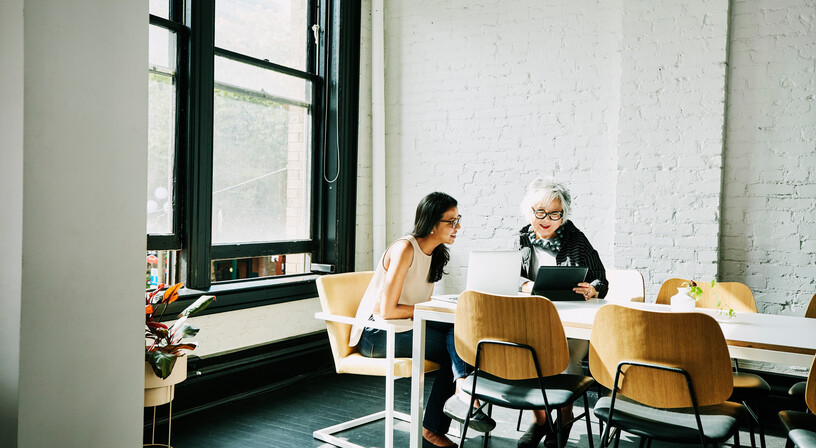 Two female colleagues talking at a meeting table