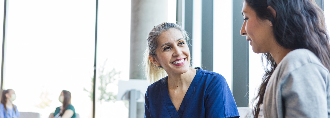Doctor smiles as she listens to the patient 