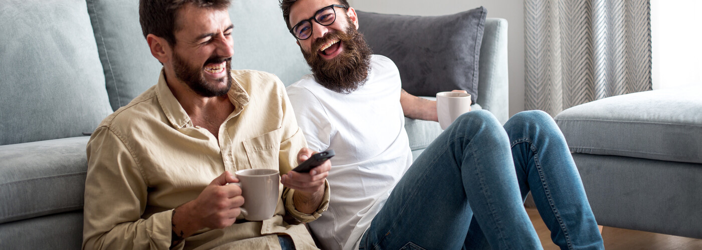 Two men laughing drinking soothing tea at home