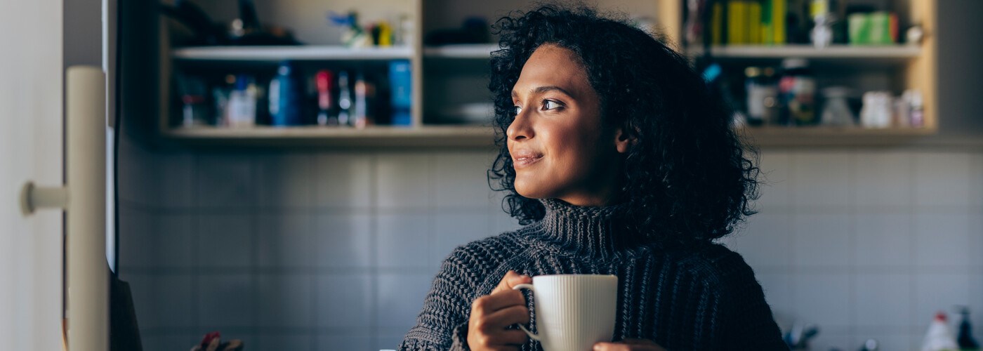 smiling woman drinking a hot cup of tea