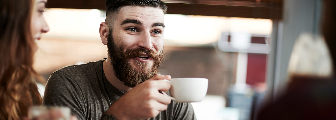 Calm man catching up with friends drinking tea