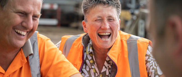 Colleagues wearing orange bibs laughing on a break