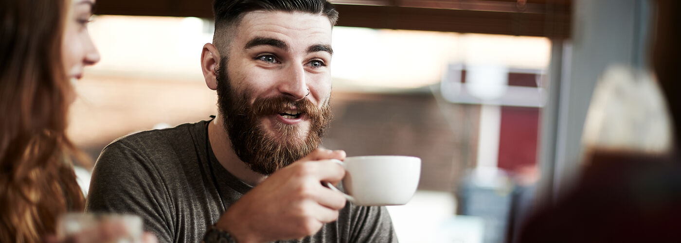 A man drinking coffee, smiling