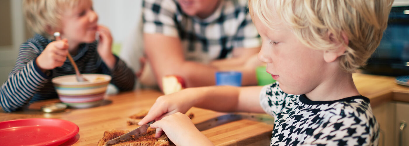 little boy buttering a slice of toast