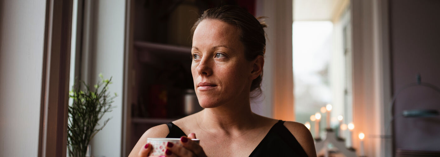 Lady drinking tea with a concerned expression, anxious about health