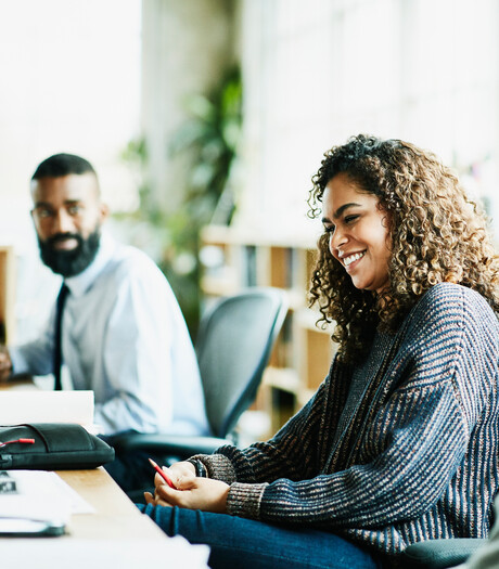 Laughing coworkers in discussion at workstation in office